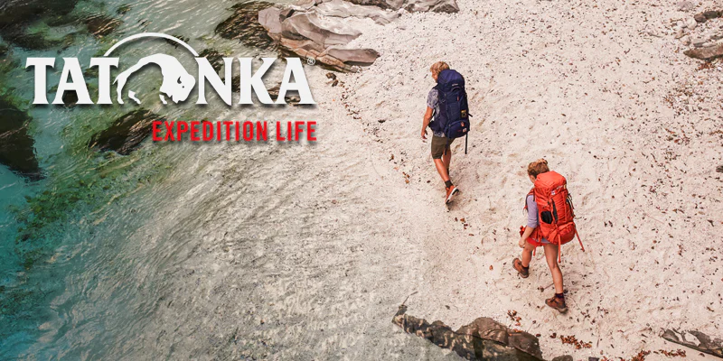 Frau steht am Bergsee mit Hund auf dem Rücken